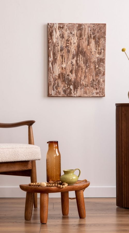 Retro and bright space of living room with mock up poster frame, wooden side table, beige armchair ,green pillow and elegant personal accessories. Beige wall. Minimalist home decor. Template.